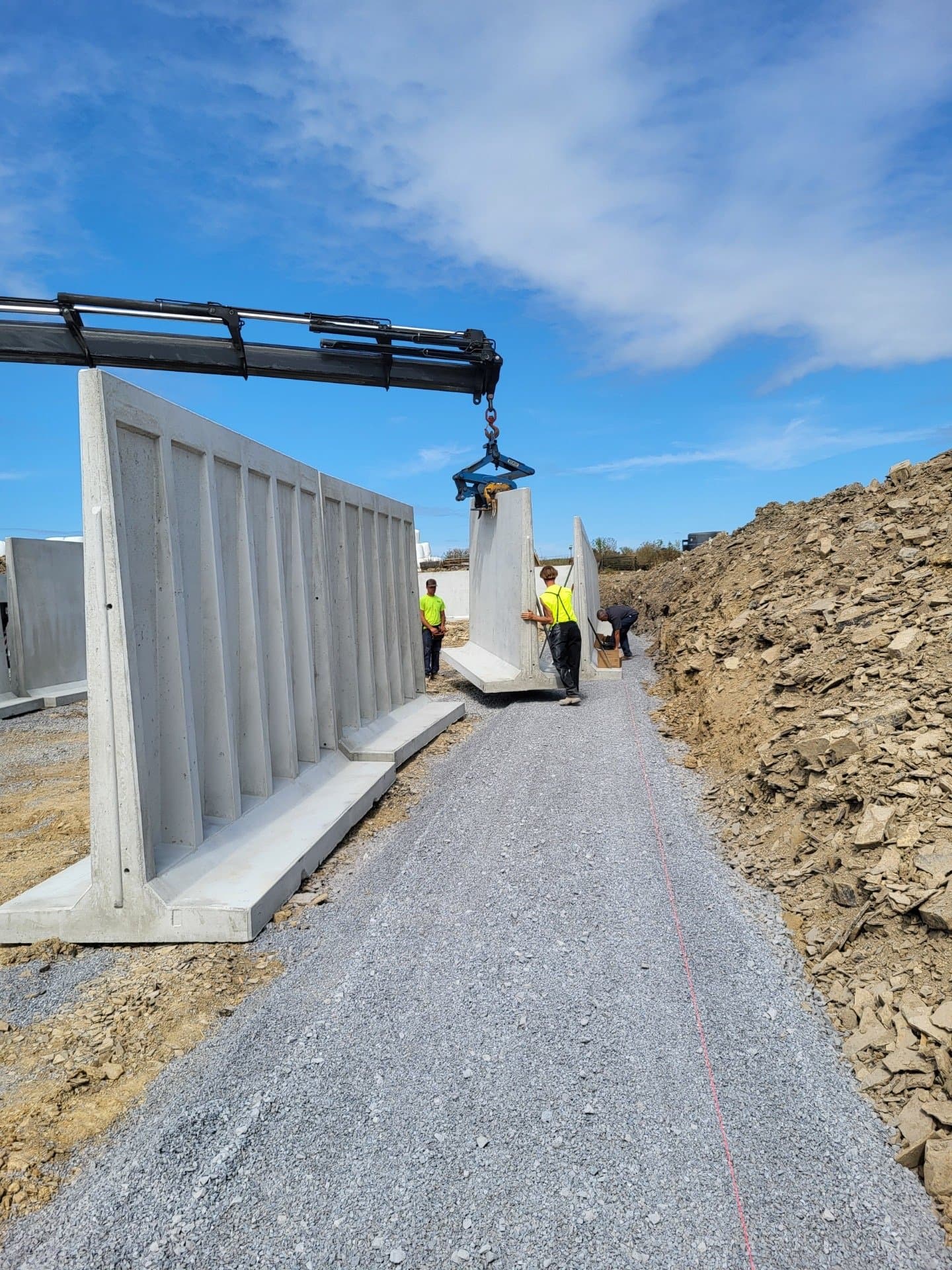 Boom truck setting precast retaining wall blocks on a Bedford site
