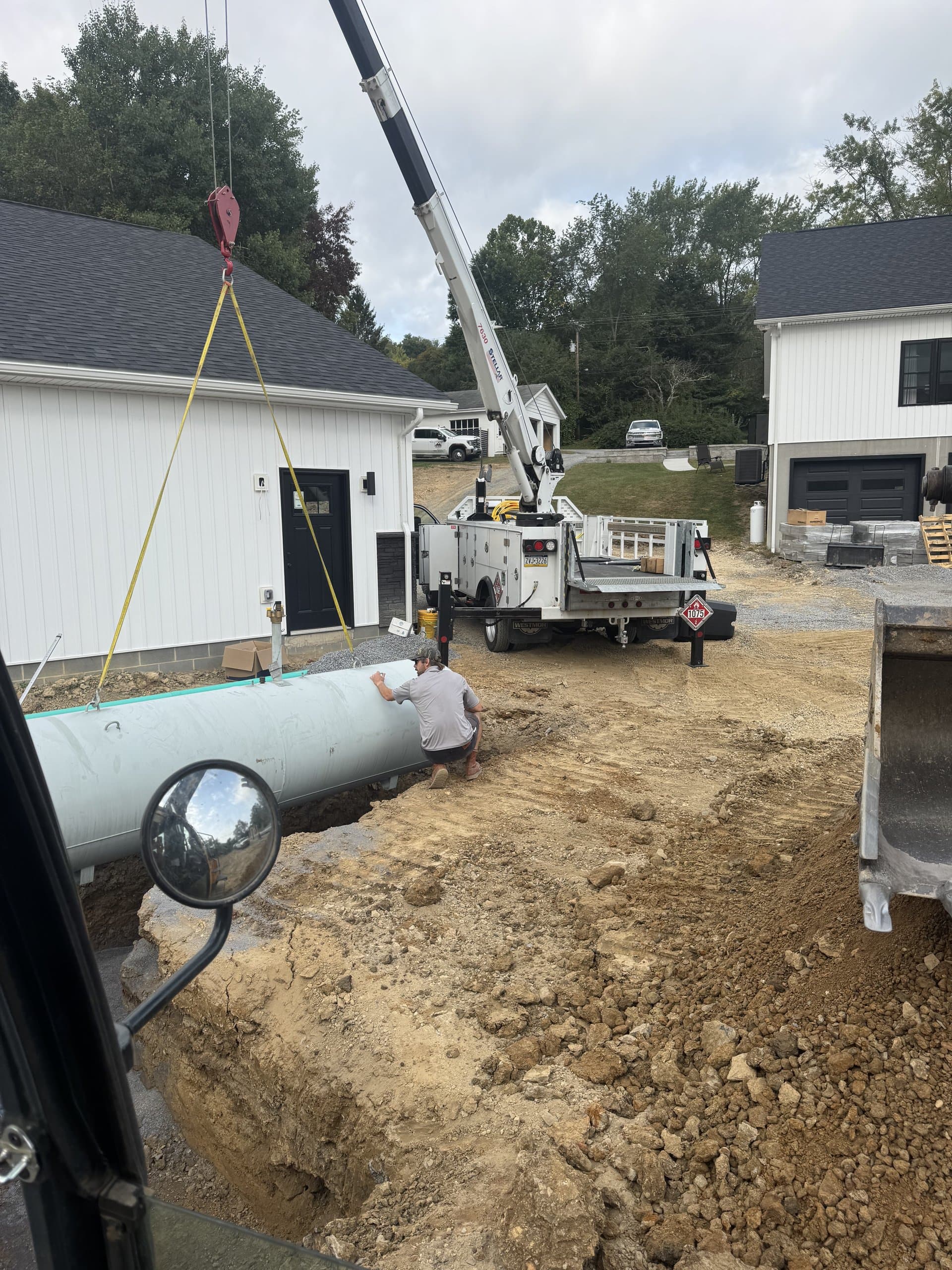 Boom truck setting concrete drainage pipe next to a Bedford home