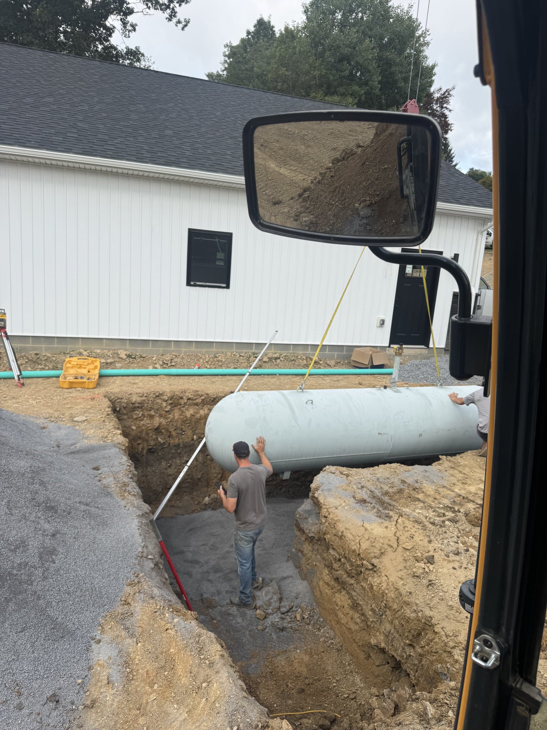 Crew setting concrete drainage pipe on a residential site