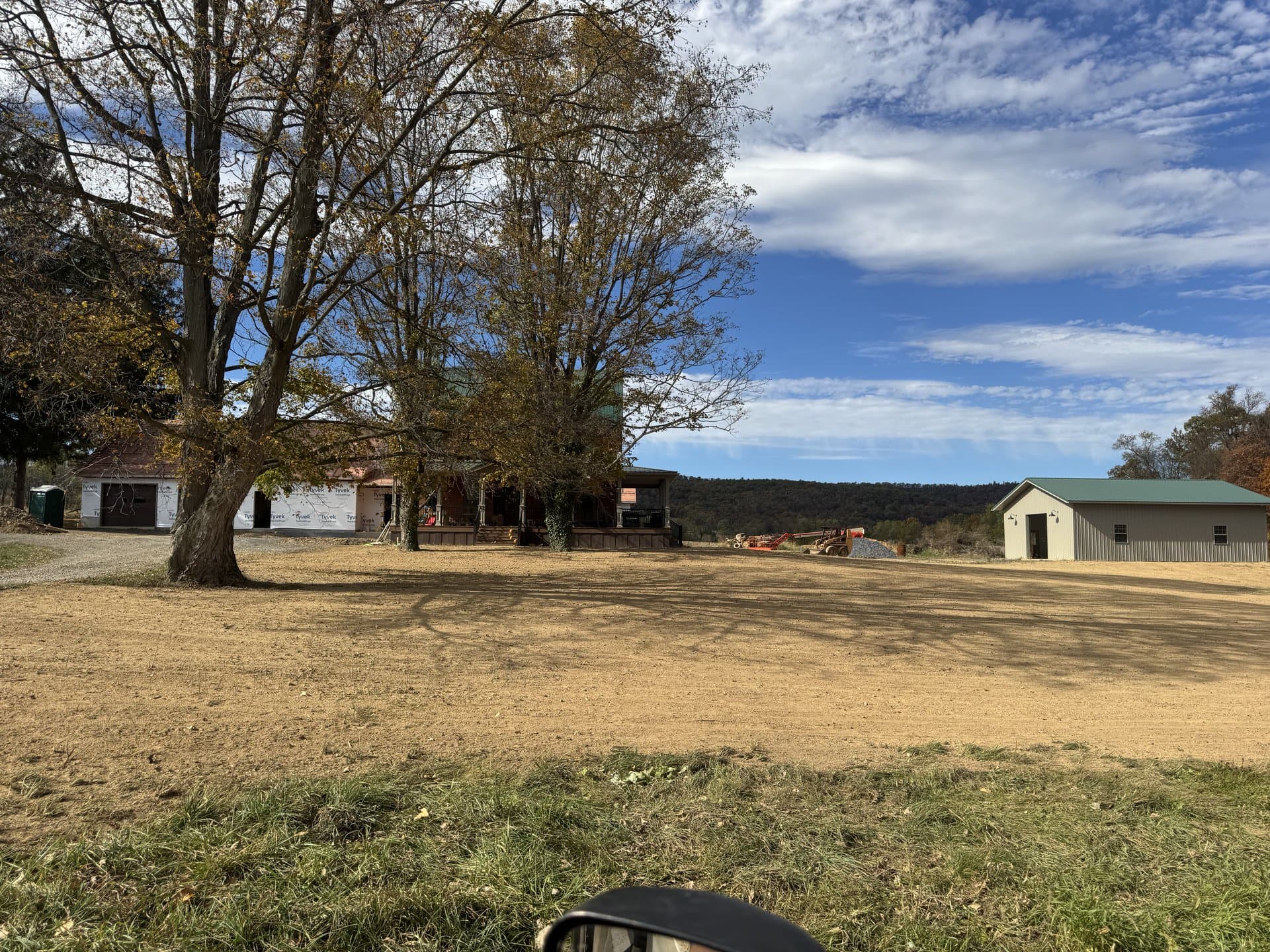 Wide rough-graded job site beside the outbuilding