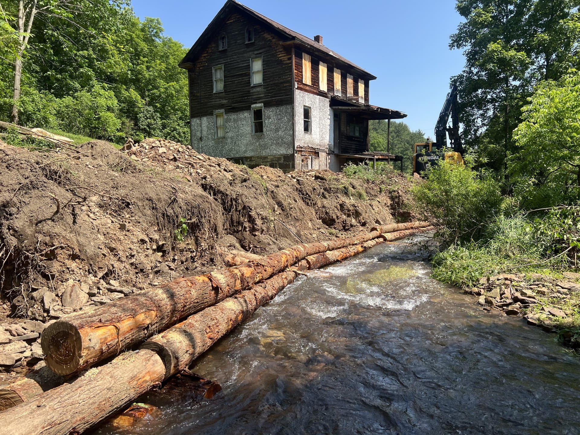 Historic wooden building protected by streambank restoration with log deflectors