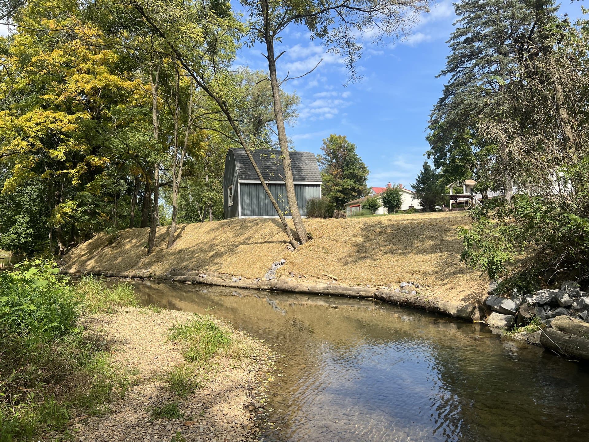 Residential streambank restoration with house above on the hillside in fall